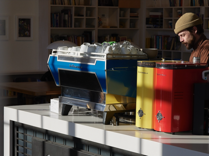 a blue espresos machine next to a yellow grinder and a red grinder at blueprint coffee in st. louis